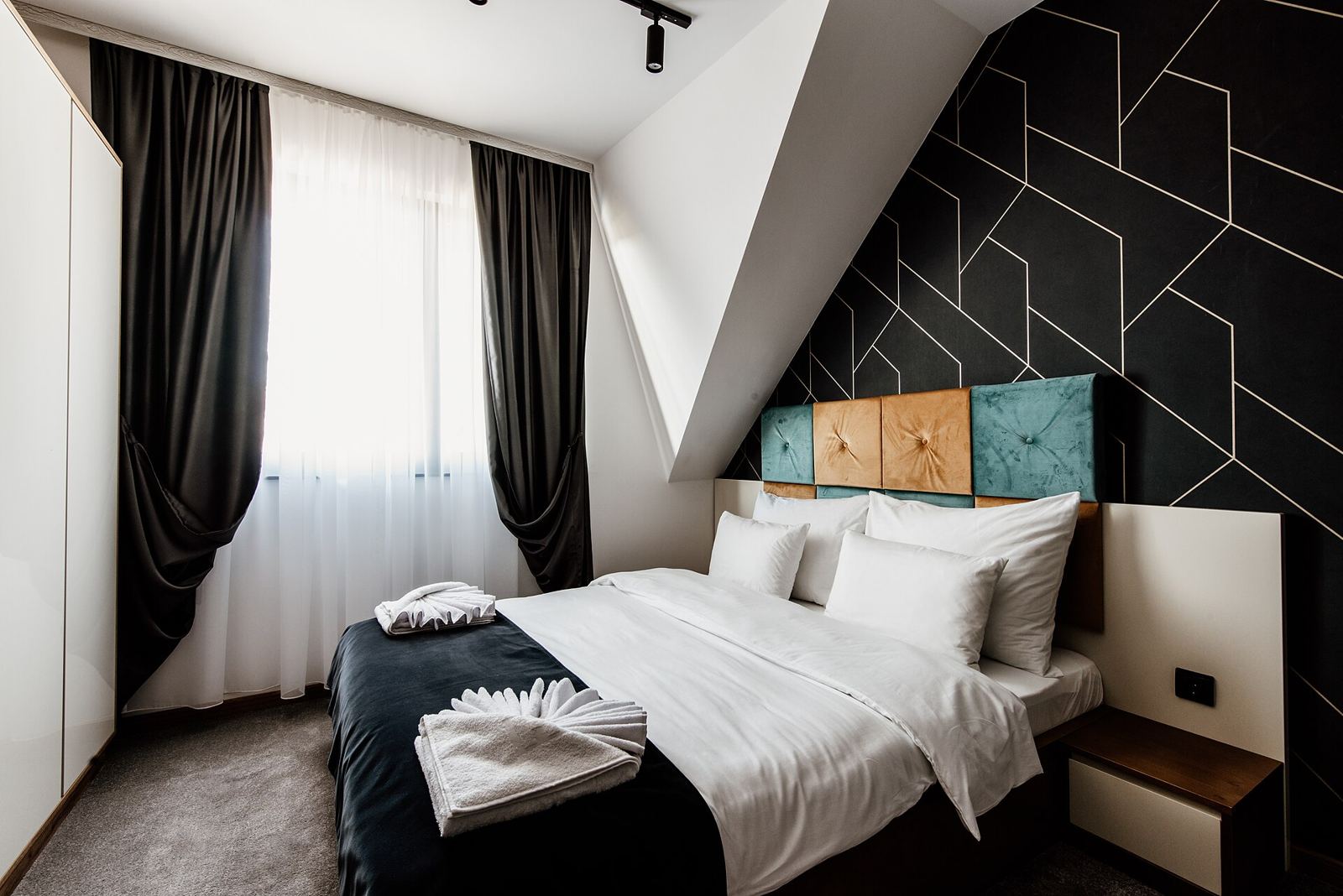 A staged bedroom with black and white linens and dramatic drapes